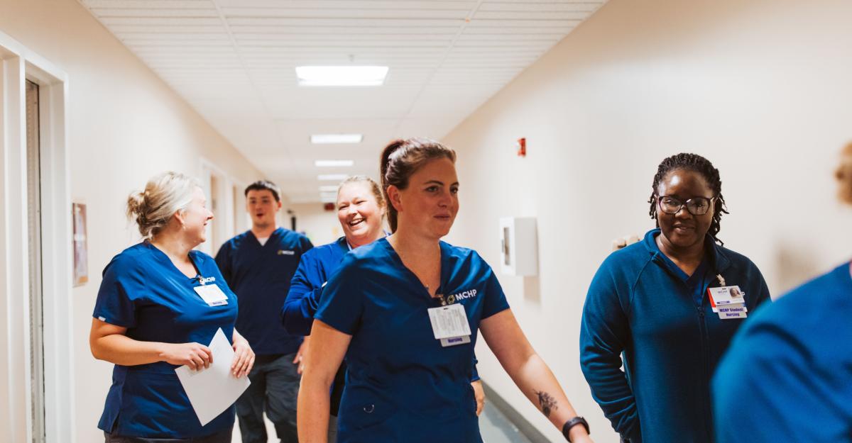 Nursing students wearing navy blue scrubs walk to class together.
