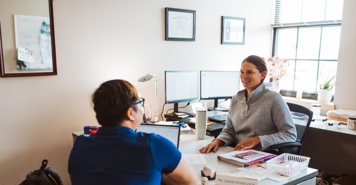 A student meets with a faculty member in their office.  They are both seated at a desk. 