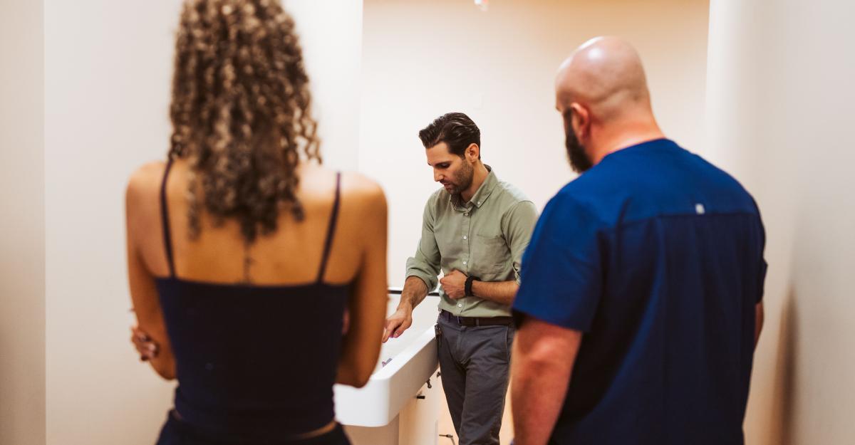 A faculty member lectures to two students looking at an x-ray.