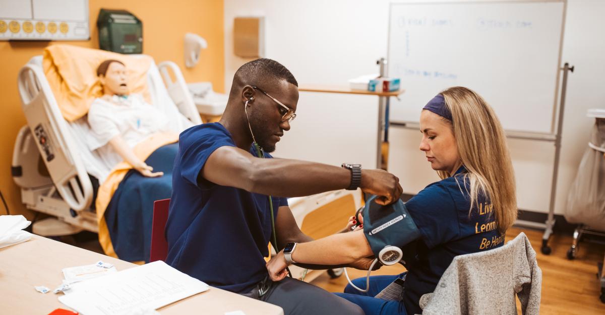 A nursing student practices using a blood pressure cuff on an instructor.